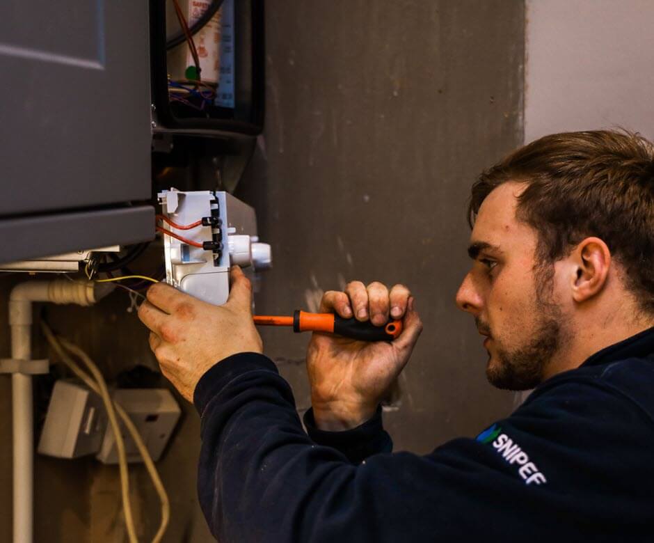 Qualified heating engineer diagnosing and repairing a boiler in poor condition.