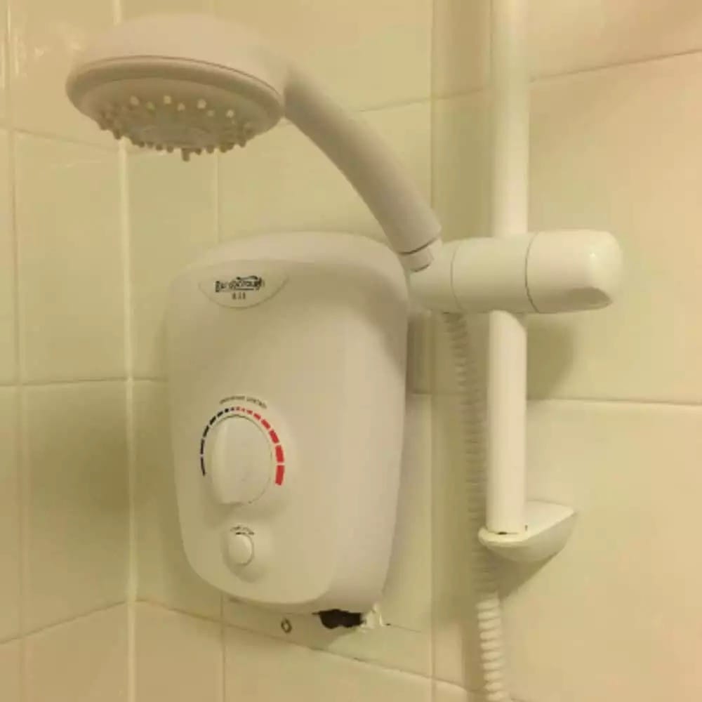 A broken Gainsborough electric shower in an Edinburgh home on a tiled wall in bathroom.