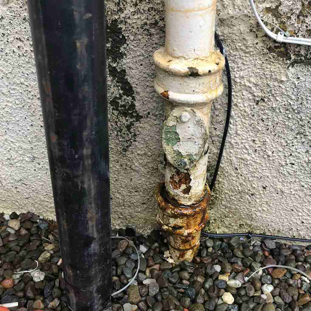 This rusty cast iron down pipe is leaking and needs repaired.